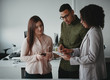 © StratfordProductions - Group of multiethnic young concentrated businesspeople using digital tablet at workplace