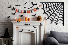 Halloween Decorations On White Fireplace With Paper Spiderweb And Grey Couch