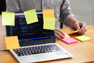 tasks on sticky note cards on laptop computer with source code program of business software developm