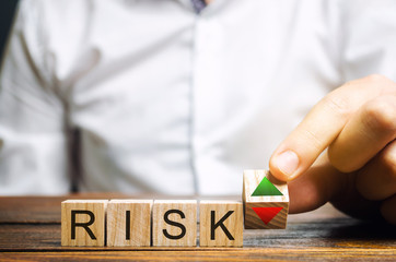 Wall Mural - businessman puts wooden blocks with the word risk and up and down arrows. business risk management c
