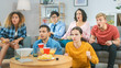 © Gorodenkoff - At Home Diverse Group Friends Watching TV Together, Eating Snacks and Drinking Beverage. They Probably Watching Sports Game, Movie or Sitcom TV Show. Young People Having Fun Together.