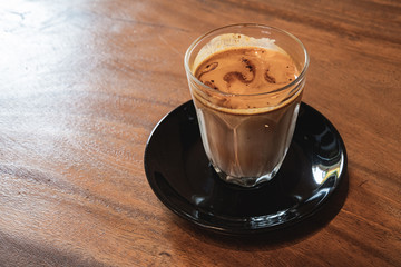 Coffee with milk in small  glass on black steel background