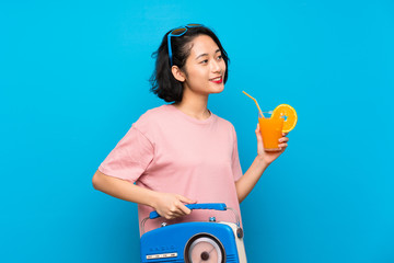 Wall Mural - Asian young woman over isolated blue background holding a radio