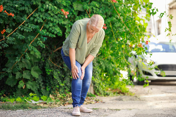 Sticker - Mature woman suffering from pain in knee outdoors