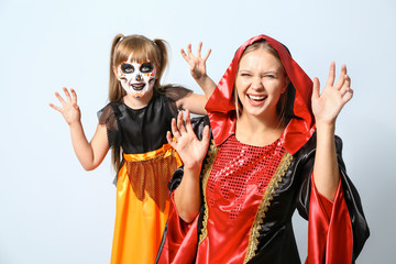 Canvas Print - Mother with little daughter in Halloween costumes on light background