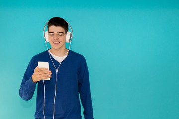 Wall Mural - young teenage man with mobile phone and trendy headphones isolated on color background