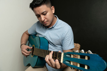 Boy playing acoustic guitar on a bench