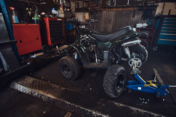 ATV with broken wheel at auto service workshop is waiting to be fixed.