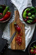 Freshly Picked Red And Green Organic Peppers, Anaheim, Shishito, Ancho Pepper, Sliced Red Pepper On Olive Wood Cutting Board With Small Knife, Pickling Summer Produce, Bowls Full Of Peppers