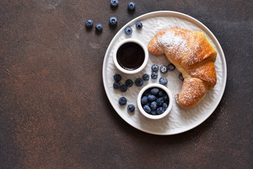 Wall Mural - Croissant with chocolate sauce for breakfast. On a brown concrete background.