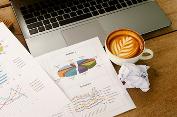 Wall Mural - Hot coffee white cups with crumpled paper and document chart and labtop computer for business finance concept