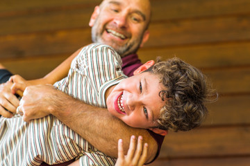 Hispanic father sitting and hugging his son.