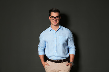 Wall Mural - Handsome young man in stylish clothes with glasses on dark background