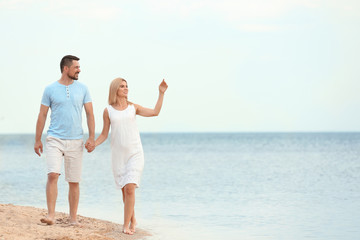 Wall Mural - Happy romantic couple walking on beach, space for text