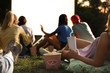 © New Africa - Young people with popcorn and drink watching movie in open air cinema, closeup
