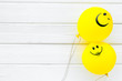 © 9dreamstudio - Happiness emotion. Yellow balloon with smile on white wooden background top view space for text