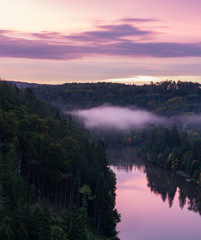  Close up to Vltava river from vantage point with fog and trees at sunrise, blue hour