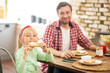 © zinkevych - Funny girl biting toast while having breakfast with dad