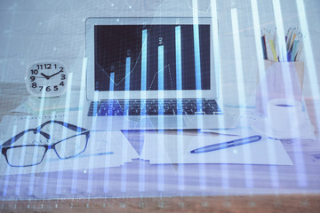 Stock market graph on background with desk and personal computer. Double exposure. Concept of financial analysis.