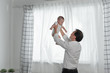 © ronnachaipark - Happy family father and toddler son playing and laughing, joyful father having fun throws up in the air