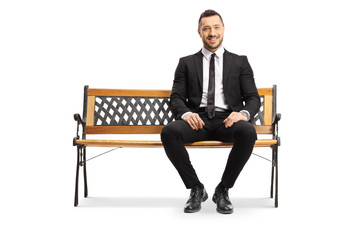 Wall Mural - Young businessman sitting on a bench and smiling