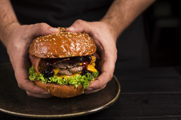 Hands holding double burger with cheese