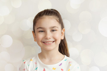 Portrait of happy smiling child girl on light background. Positive emotions.