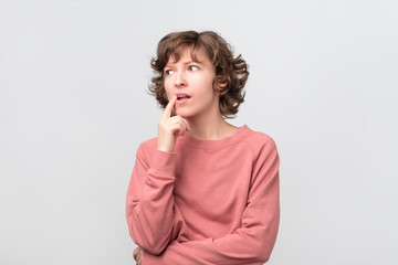 Young curly woman thinking and pondering over something