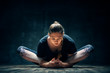 Young woman practicing yoga doing reclined goddess pose asana in dark room