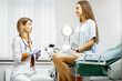 Gynecologist preparing for an examination procedure for a pregnant woman sitting on a gynecological chair in the office