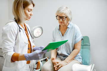 Senior woman sitting on the gynecological chair during a medical consultation with gynecologist. Concept of women's health during a menopause