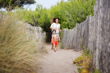 Mother And Son Happily Running On Sandy Path At Beach