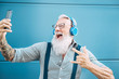 © Alessandro Biascioli - Senior crazy man taking self video while listening music with headphones - Hipster guy having fun using mobile smartphone playlist apps - Happiness, technology and elderly lifestyle people concept