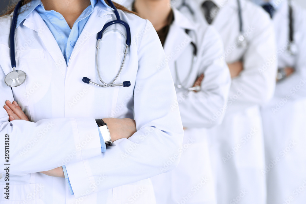 Group of modern doctors standing as a team with arms crossed in hospital office. Physicians ready to examine and help patients. Medical help, insurance in health care, best desease treatment and - obrazy, fototapety, plakaty 