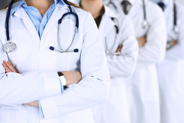 Group of modern doctors standing as a team with arms crossed in hospital office. Physicians ready to examine and help patients. Medical help, insurance in health care, best desease treatment and