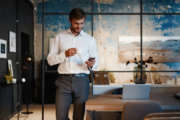 handsome young bearded business man in office using mobile phone indoors.