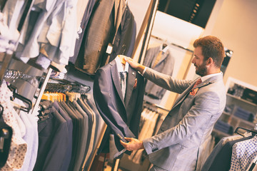 Canvas Print - Handsome man choosing jacket in a shop