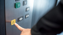 Male Forefinger Pressing On Emergency Stop And Alarm Button In Elevator (lift). Mechanical Engineering Concept
