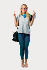 Poster - Full body of Student girl with glasses with fingers crossing and wishing the best. Making a wish. on grey background