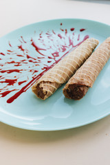 Wall Mural - Red caramel and waffle tubes with sweet filling on plate