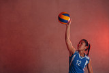 Young Asian woman volleyball player in blue uniform innings ball action
