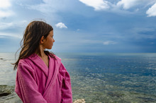 Young Girl In Bathrobe On The Beach, Stormy Weather In Background.