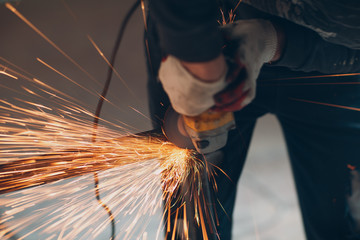 Craftsman sawing metal with disk grinder saw in workshop