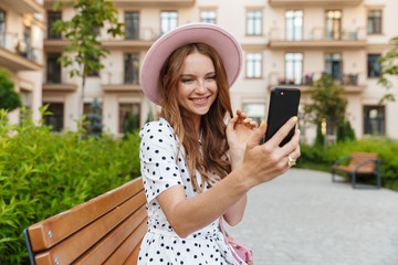 Wall Mural - Young redhead woman talking by mobile phone.