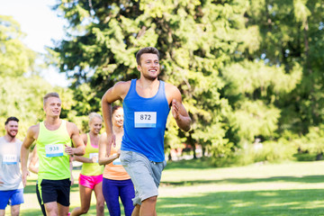 Poster - fitness, sport, race and healthy lifestyle concept - group of happy people or sportsmen running marathon with badge numbers at summer park