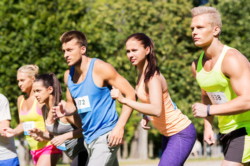 Sticker - fitness, sport, race and healthy lifestyle concept - group of people or sportsmen with badge numbers on start of running marathon at summer park