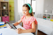 © Syda Productions - children, education and technology concept - happy student girl in headphones with tablet computer at home desk