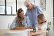 © goodluz - Little girl doing homework, mom and grandma watching her