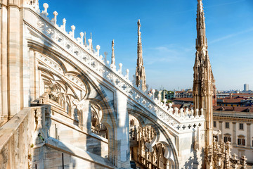 White statue on top of Duomo cathedral and view to city of Milan