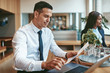 © Flamingo Images - Smiling businessman reading paperwork and using a laptop at work